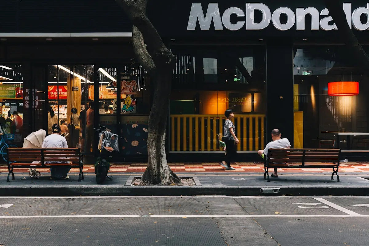 People sitting on benches outside a mcdonald's restaurant.