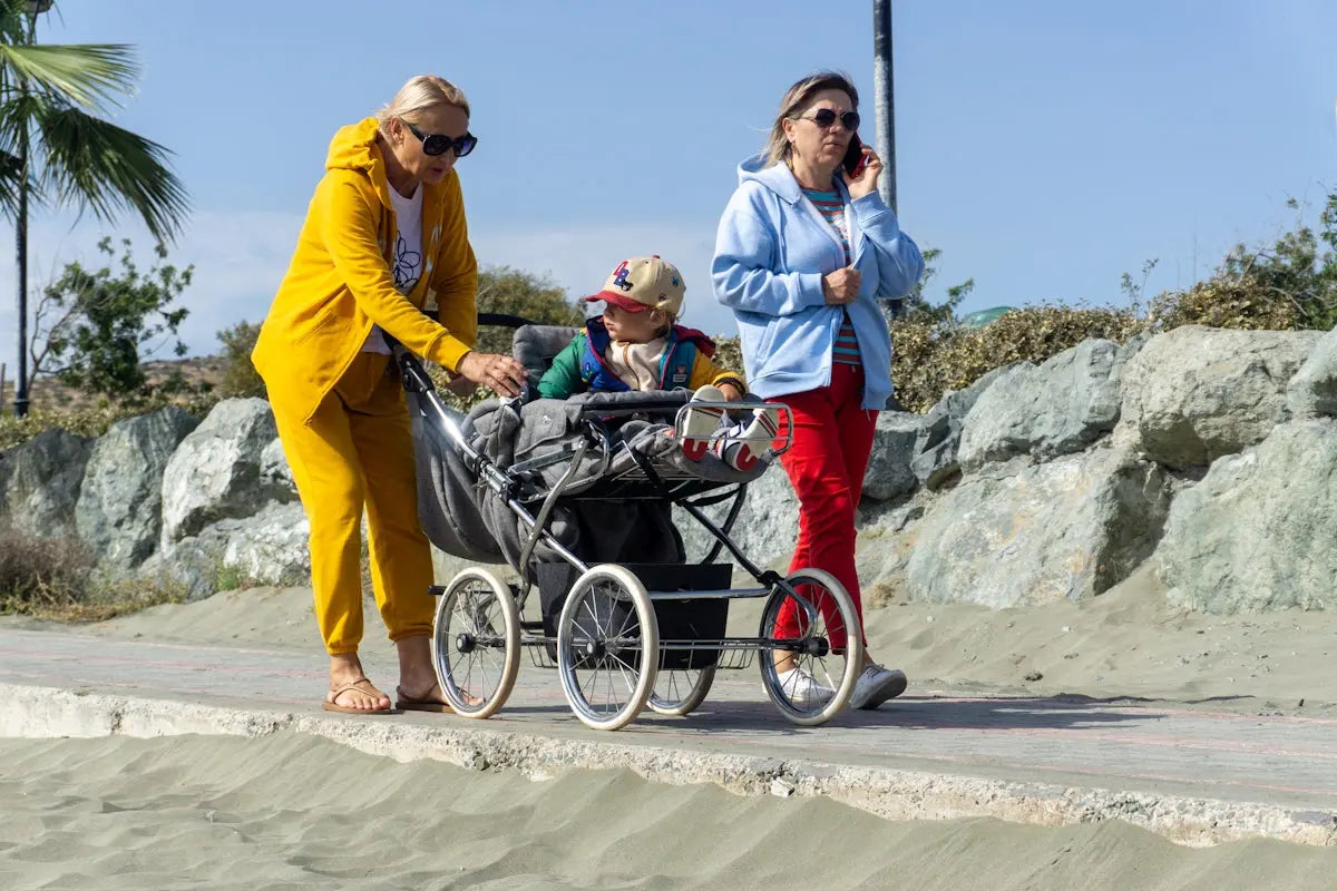 Two women walk with a baby stroller.